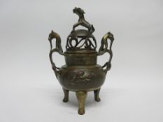 Oriental Koro and cover, the cover with dog finial, the base on three feet decorated in relief