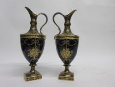 Pair of Royal Crown Derby ewers decorated in neo-classical style in gilt on a dark blue ground (