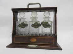 Edwardian oak three-bottle tantalus applied with three plated spirit labels for Brandy, Whisky and