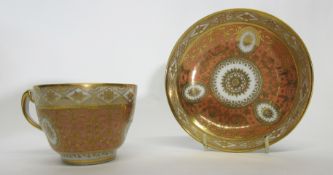 Early 19th century Coalport cup and saucer with a gilt design on salmon ground, pattern number