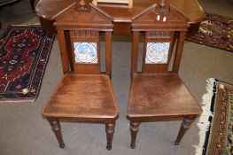 Pair of late 19th century mahogany hall chairs, the splat backs each inset with ceramic tiles