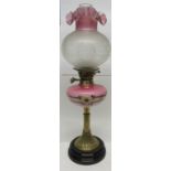 Oil lamp with decorated brass column and pink glass reservoir decorated with flowers and globular