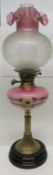 Oil lamp with decorated brass column and pink glass reservoir decorated with flowers and globular