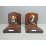 A pair of black forest carved bookends with models of foxhound heads to each plynth