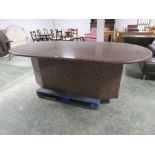 A contemporary, heavy marble table, red ground with black flecks, and central pedestal base.
