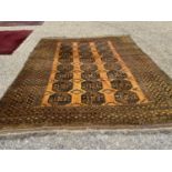 An Afghan gold ground carpet having 3 rows of elephant foot designs within a geometric border 9'7