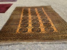 An Afghan gold ground carpet having 3 rows of elephant foot designs within a geometric border 9'7