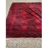An Afghan red ground carpet with 3 rows of elephant foot designs within a quadruple border 10'6 x