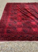 An Afghan red ground carpet with 3 rows of elephant foot designs within a quadruple border 10'6 x