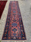 A Caucasian pink ground runner having a panel of stylised geometric and foliate motifs within a blue