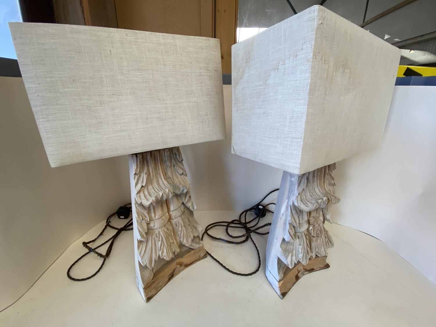 Pair of heavily carved wooden table lamps with rectangular canvas shades CONDITION: some wear -