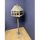 A decorative pedestal iron bird table, in the form of a house, with bird finial to roof