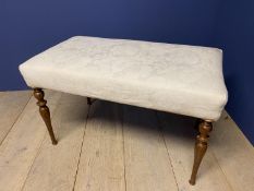 A rectangular seat upholstered stool in cream damask fabric on turned mahogany legs. 89cmW x 50 x