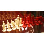 An incomplete set of 19th century turned chess pieces, one side in natural, the other red stained,