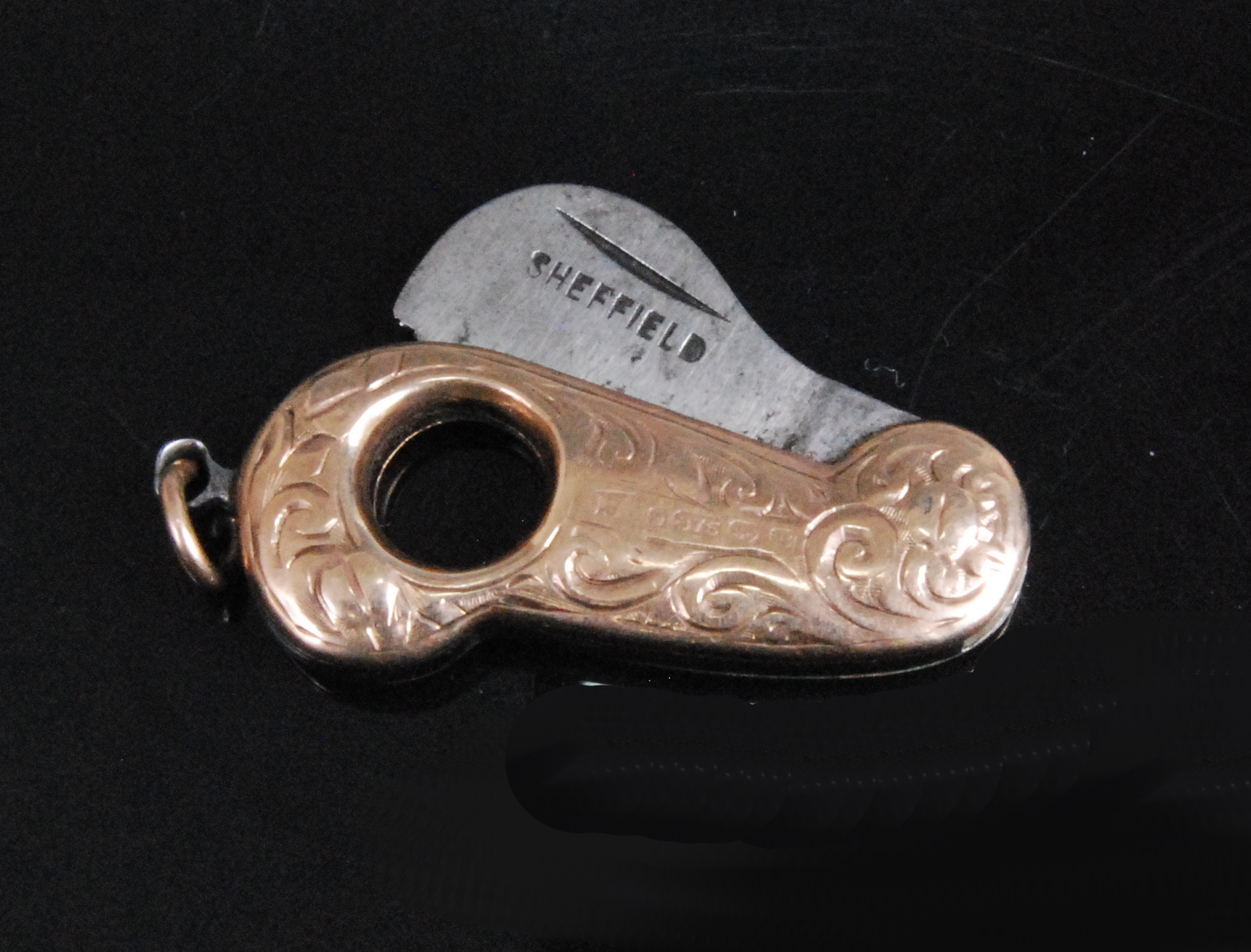 An early 20th century 9ct gold pocket cigar cutter of shaped form with engraved decoration having