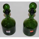 A pair of mid-20th century green glass decanters and stoppers, each of mallet shape, h.28cm