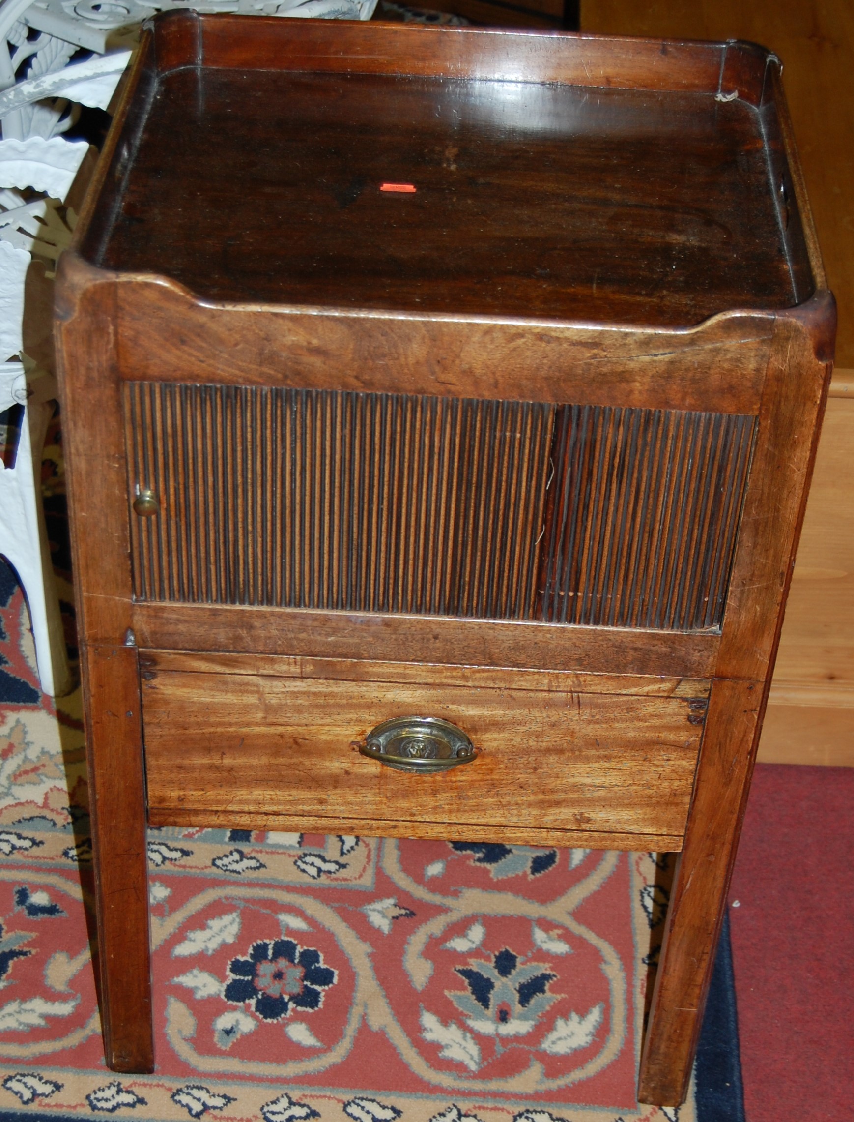 An early 19th century mahgoany round cornered tray-top nightstand, having tambour door over single