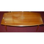 A 1970s teak low coffee table, having bowed sides, on turned tapering supports, length 104cm