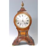 A late 19th century mahogany and inlaid balloon shaped mantel clock, having brass pineapple finial