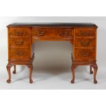 A figured walnut kneehole writing desk, circa 1930, the top with gilt tooled leather inset writing