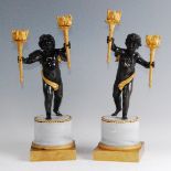 A pair of circa 1900 French bronze and gilt bronze putti candelabra, each modelled in standing