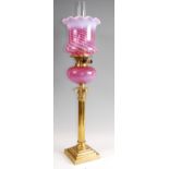 A Victorian lacquered brass pedestal oil lamp, having vaseline tinted cranberry glass shade with