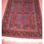 A Persian woollen rust and blue ground carpet , decorated with three rows of stylised medallions