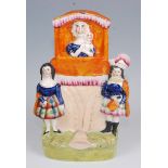 A 19th century Staffordshire flatback figure of a Punch & Judy Show, having central Punch puppet