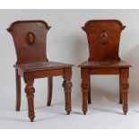 A pair of late Victorian figured walnut hall chairs, the backs with convex oval cartouche with