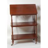 A late Victorian mahogany three-tier whatnot, having a hinged lectern top and raised on slender