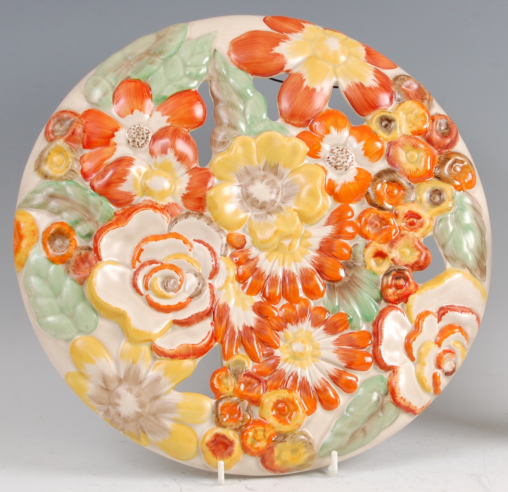 A 1930s Clarice Cliff pottery circular wall charger, pierced and floral stylised moulded,