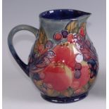 A contemporary Moorcroft pottery jug in the Finches & Fruit pattern, of slightly bulbous form,