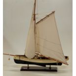A painted wooden model of a yacht with full rigging on plinth base