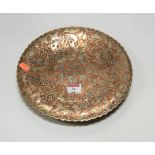 An early 20th century eastern copper dish of shaped circular form, relief decorated with flowers and