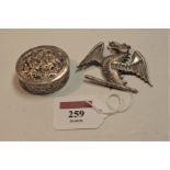 A white metal badge in the form of a dragon with outswept wings, having pin back fitting, w.7cm;