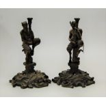 A pair of brass figural candlesticks, each in the form of Pan in seated pose on pierced C-scroll