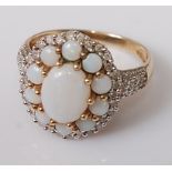 A 9ct gold opal and diamond dress ring, the large oval setting having a centre cabochon opal flanked