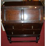 An early 20th century oak slopefront two drawer writing bureau, raised on bulbous turned supports,