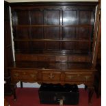 A large 18th century style joined oak dresser, the wavy cut frieze over three tier open plate rack