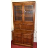 A contemporary Ercol mid elm wall unit, having twin bevelled glazed upper doors over fall front