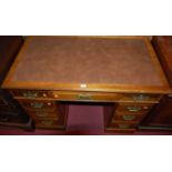 An Edwardian walnut and rexine inset twin pedestal writing desk, the nine drawers with pierced brass