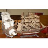 Four various model sailing vessels, each raised on stands