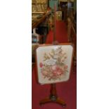 An early Victorian rosewood pedestal pole screen, having a large floral tapestry inset adjustable