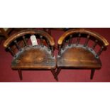 A pair of rustic provincial pitched pine tub elbow chairs, each with turned upright supports, on