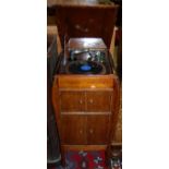 A 1930s Apollo oak freestanding gramophone, the hinged cover enclosing turn table over four cupboard