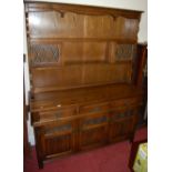 A contemporary Old Charm linenfold moulded oak dresser having lead glazed inset upper doors, width