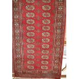 A Persian woollen red ground Bokhara hall runner, 250 x 79cm