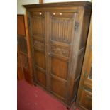 A joined and linenfold moulded oak double door wardrobe, having panelled doors and exposed