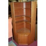 A 1970s teak corner unit, having open fixed shelves over single lower cupboard door