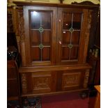 A Flemish carved oak display cabinet, having twin lead glazed upper doors over twin relief carved